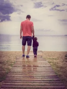 Man and toddler strolling seaside boardwalk