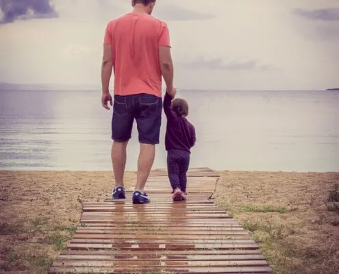 Man and child walking on beach boardwalk