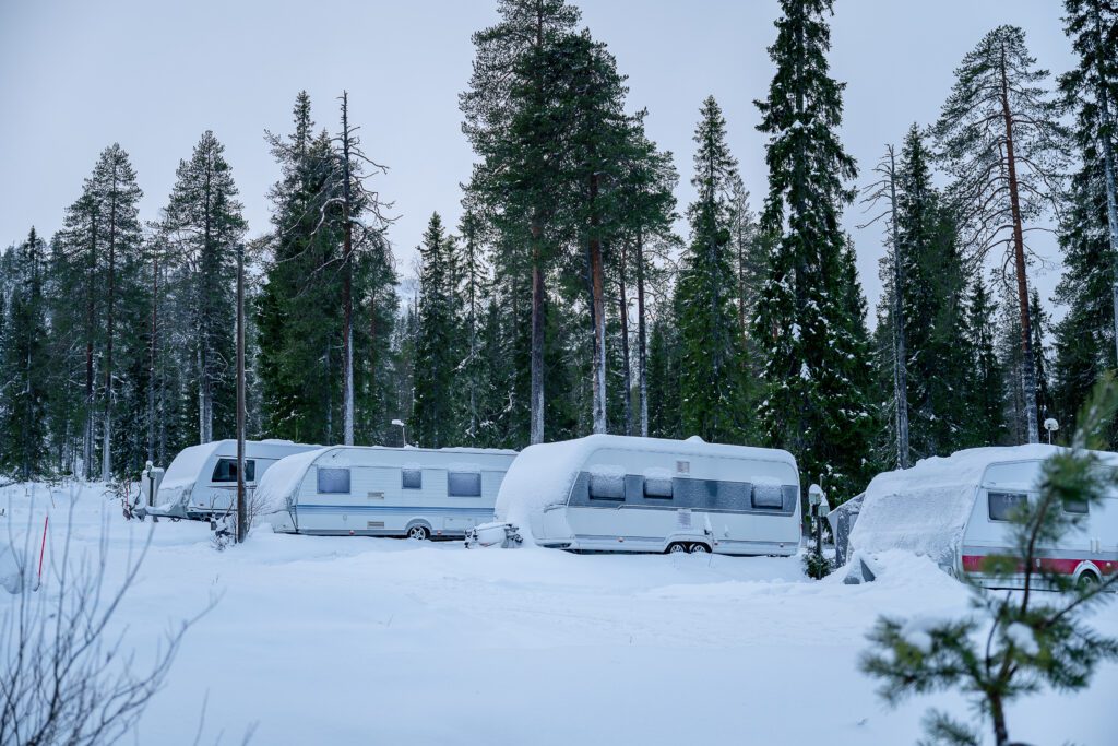 Caravan of camper cars in winter forest. Camping in Lapland Finland. Winter camping concept
